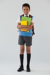 Schoolboy in school uniform with school bag on white background