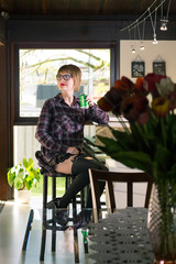 Blonde young woman sitting by the bar drinking a beer