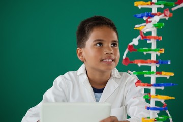 Smiling schoolboy experimenting molecule model in laboratory