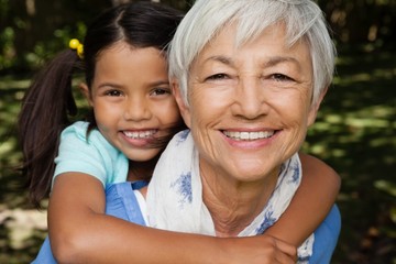 Close-up portrait of smiling grandmother giving piggyback to