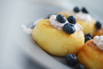 traditional morning homemade breakfast cottage cheesecakes with sour cream and berries.