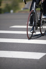 Fototapeta na wymiar Cyclist crosses the city road with pedestrian crossing on road bike