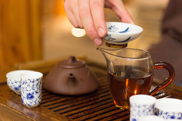 Hand of the master keep the cup. Traditional Chinese tea drinking ceremony.