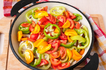 Sliced vegetables in a frying pan stand on table