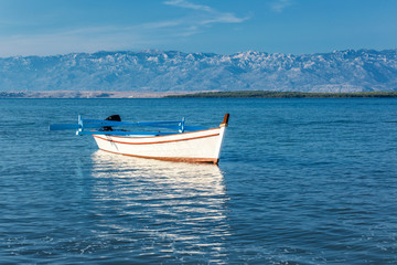 A white boat at sea. The national park Paklenica of Croatia in the background, southern slopes of Velebit mountain, Europe.