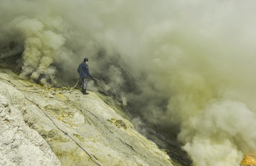 Kawah Ijen ranger trying to put of the smoke by spraying water from acid lake to enhance the sulphur production which is affected by flames and smoke, Indonesia