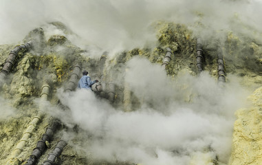 Kawah Ijen ranger trying to put of the smoke by spraying water from acid lake to enhance the sulphur production which is affected by flames and smoke, Indonesia