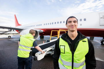 Worker Smiling While Colleague Working On Runway