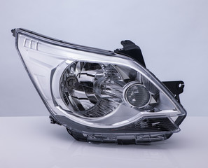 closeup of a car headlight on bright background with reflection. isolated 
