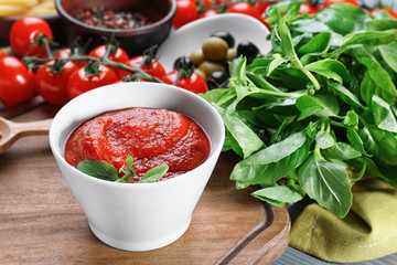 Bowl with tasty tomato sauce for pasta on wooden board