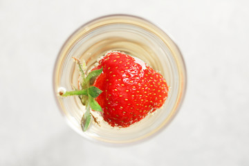 Glass of delicious wine with strawberry on white background