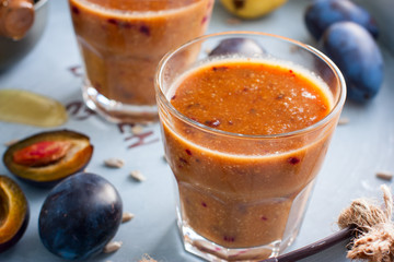 Fruity smoothies with a plum in glass glasses on a metal tray, horizontal