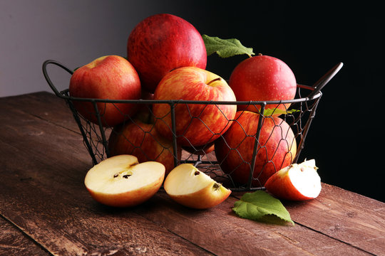 Ripe red apples with leaves on wooden background
