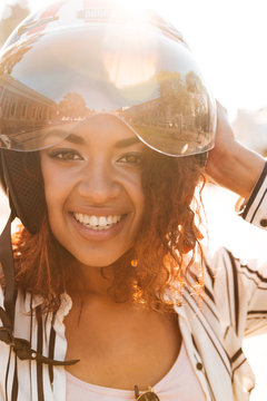 Vertical close-up image of happy african woman in moto halmet