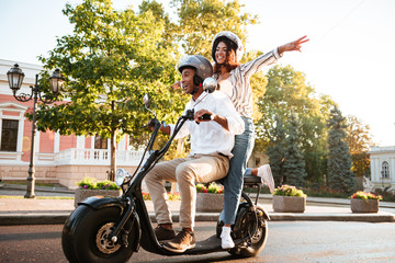 Full length picture of happy african couple rides on motorbike