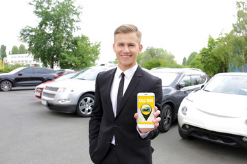 Young man calling taxi by cellphone outdoors