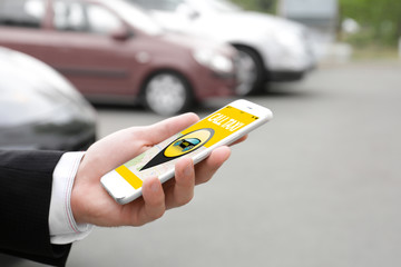 Young man using application on phone for calling taxi outdoors