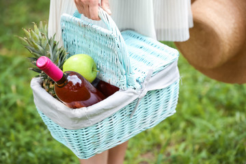 Woman carrying picnic basket with fruits and wine in park