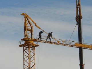 Men erecting large yellow crane