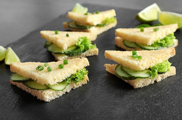 Tasty sandwiches with fresh cucumber on slate plate