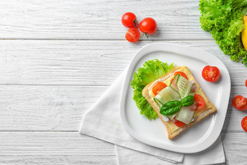 Plate of tasty sandwich with fresh cucumber on wooden background