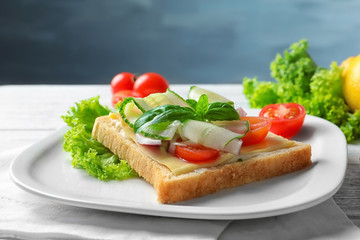 Plate of tasty sandwich with fresh cucumber on table