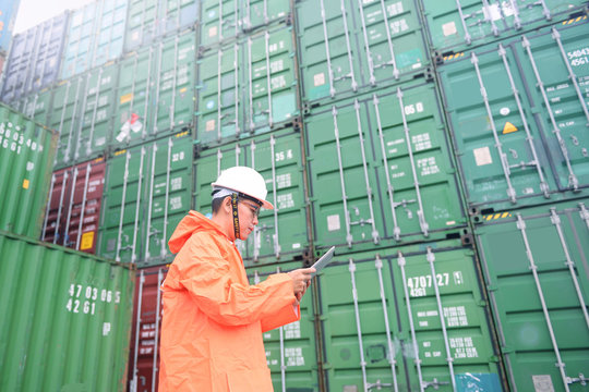 Foreman Putting Rain Coat And Using Tablet While Hard Working At Container Depot.