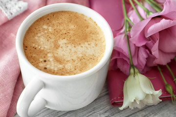 Cup of aromatic morning coffee and flowers on table