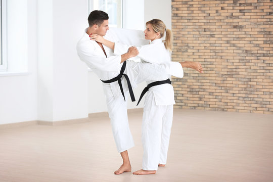 Young man and woman practicing karate in dojo