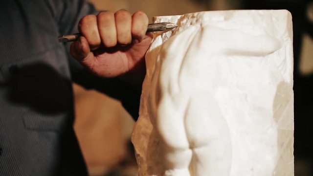 Sculptor works with marble statuette 