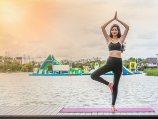 The acting setup of Yoga concept. A asian young woman doing Yoga outdoor by the lake.