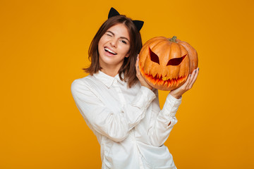 Cute teenage schoolgirl in uniform holding halloween pumpkin