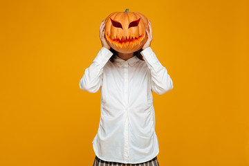 Funny teenage schoolgirl in uniform holding halloween pumpkin