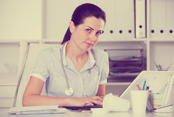 Young and smiling doctor in uniform with stethoscope