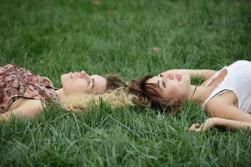 Two women lay and rest on a grass