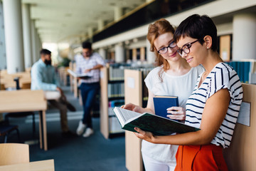 Young attractive students spending time in library