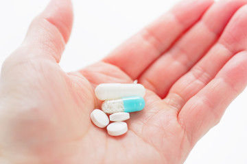 Blue capsule medicines and tablets in female hand. Prescription drugs. Concept image of medication.
