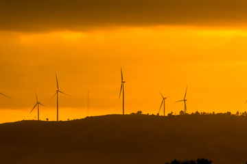 Obraz premium Wind turbines for electricity on a mountain at sunset.