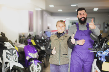 Fototapeta na wymiar happy male worker assisting female customer in repairing motorcycle in workshop