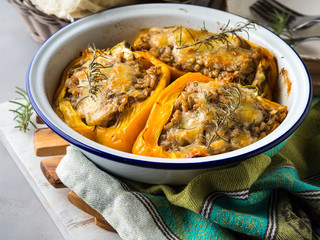 Bell peppers stuffed with barley and meat baked in enamel tin on gray