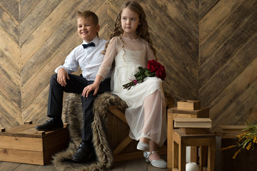 Fototapeta premium Boy and girl, brother and sister, friends with a bouquet of flowers in a beautiful studio. Childhood, friendship, porter.