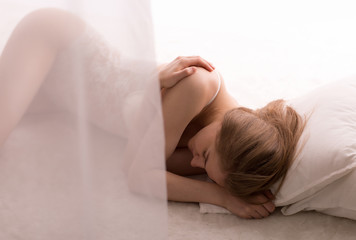 Lonely sad woman lay sleep, dream on white floor, bed unred curtains