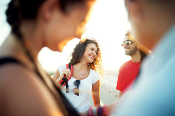 Group of young smiling friends with sunglasses and backpacks.