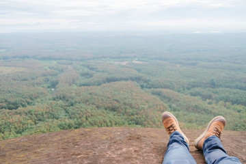 Fototapeta na wymiar Legs of Couple traveler sitting on a high mountain top in travel. Freedom concept