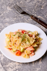 Pasta farfalle with salmon, zucchini and tomate