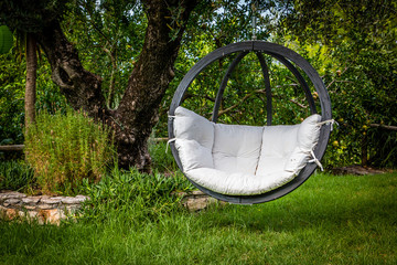 Lounge hanging chair with white pillow in the garden with green nature background