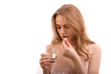 woman takes medicine pills and drinks water from glass