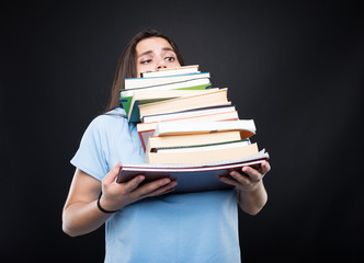 Young girl carrying heavy pile of books - obrazy, fototapety, plakaty