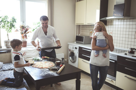 parents with two children prepare pizza in cozy
