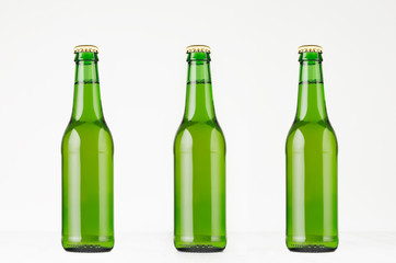 Three green longneck beer bottles 330ml, mock up. Template for advertising, design, branding identity on white wood table.